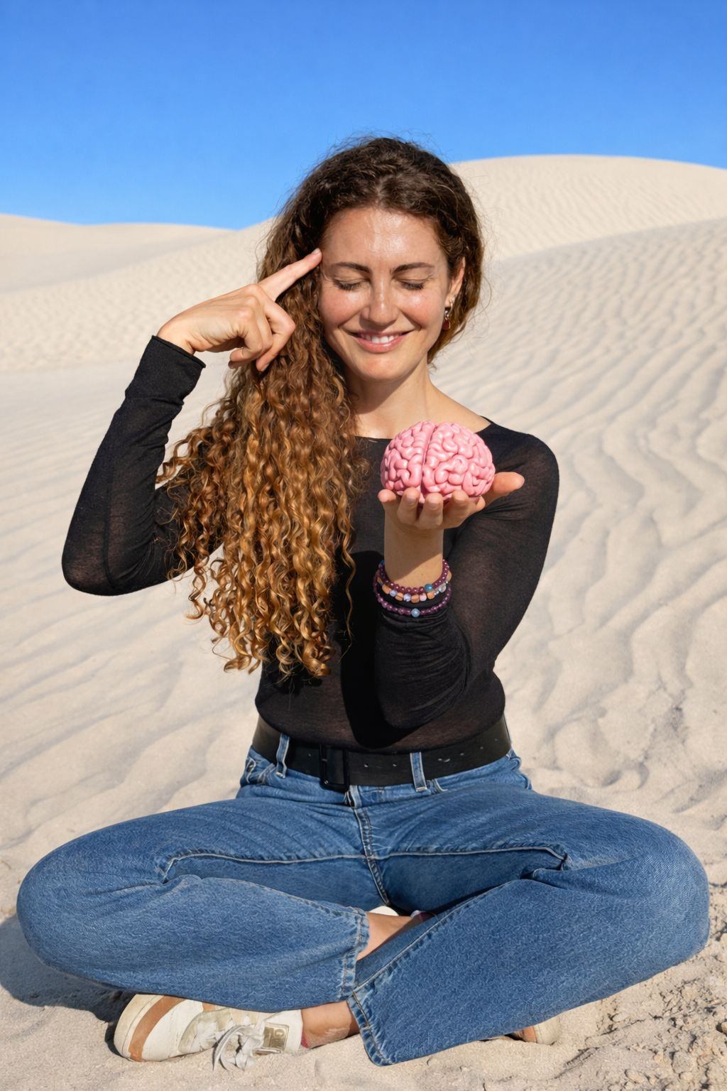 Catherine holding a model brain in the dunes